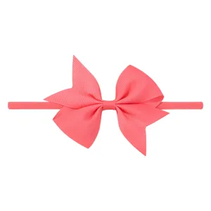 Détail rapproché d'un nœud en ruban gros-grain rose sur un bandeau élastique bébé