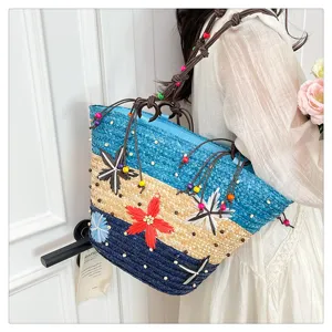 Detailed view of a woven straw tote bag with vibrant 3D flowers and blue striped pattern