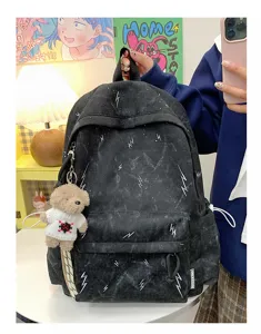 Black student backpack with white lightning print and a cute plush bear keychain.