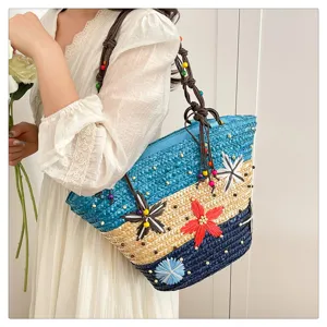 Close-up detail of a multi-color woven straw tote bag featuring 3D flowers and beaded straps