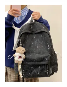 Detail view of black high-capacity school backpack with lightning patterns and bear charm