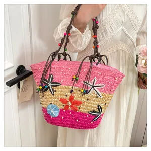 Detail of a colorful woven tote bag with 3D floral accents and beaded straps on handle