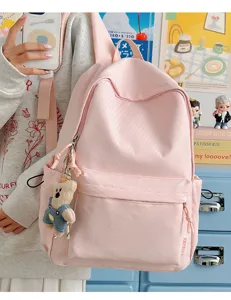 Minimalistische roze rugzak voor studenten met schattige berenhanger in scène