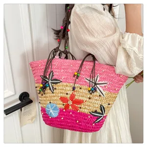 Detail of a large woven straw basket bag with colorful floral decorations and beads.