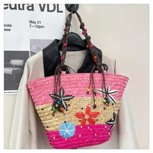 Close-up of woven straw tote bag featuring colorful flower accents and beaded straps.