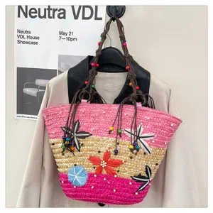 Close-up of a multi-color woven straw tote bag featuring decorative raffia flowers and beads.