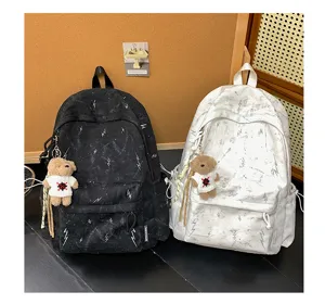 Close-up of black and white lightning print backpacks with cute teddy bear charms.