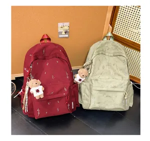 Detail of lightning pattern backpacks in burgundy and sage green with teddy bear charms