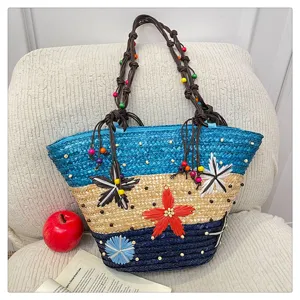 Detailed view of hand-woven straw tote bag with colorful 3D flowers and beaded handles