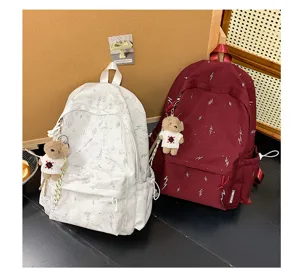 Detailed view of white and burgundy lightning bolt backpacks with cute teddy bear charms