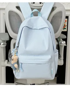 Detailweergave van een lichtblauwe minimalistische schooltas met een berenhanger