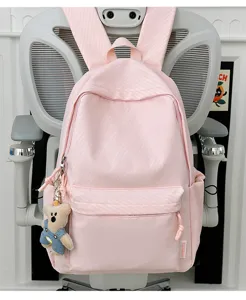 Detailopname van een roze schoolrugzak in snoepkleur met een schattige teddybeer sleutelhanger