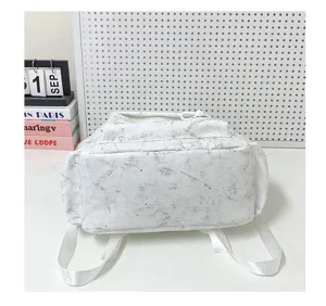Close-up detail showing the bottom construction of a white marble pattern student backpack