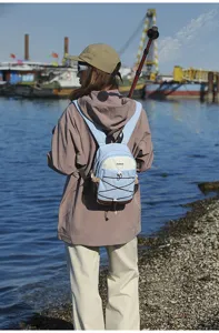 Rear view of a small color-block outdoor hiking backpack worn by a hiker at a scenic port