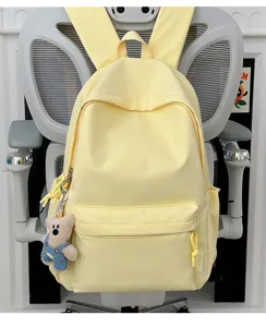 Detailweergave van minimalistische gele studentenrugzak met een schattige beer sleutelhanger