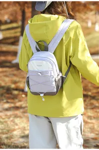 Outdoor scene of a woman carrying a small lilac color-block backpack for travel