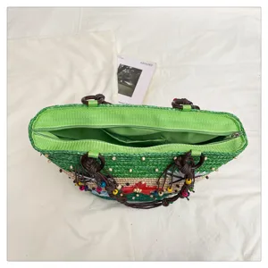 Top-down view of woven straw tote bag showing zipper closure and green lining