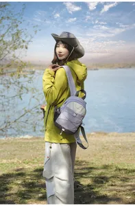 Model wearing a color-blocked small backpack during an outdoor hiking trip by the lake