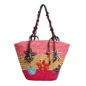 Detailed view of handcrafted flower patterns on a colorful woven straw tote bag.