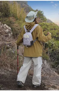 Outdoor lifestyle shot of a small color-block hiking backpack in lilac and cream colors.