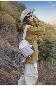 Outdoor lifestyle shot of a woman wearing a small purple and beige color-block hiking backpack