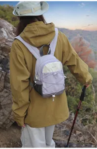 Woman wearing a purple and cream small outdoor hiking backpack during trekking in the mountains