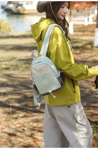Close-up of a small color-blocked outdoor backpack worn by a model in nature