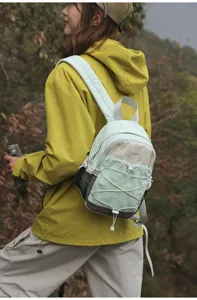 Detail view of mint green and beige contrast color-block mini backpack on outdoor hiker