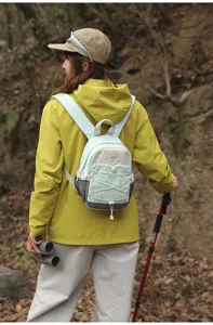 Asian female model wearing a mint green small hiking backpack for outdoor mountain scenes.