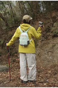 Back view of a woman wearing a mint green mini outdoor backpack during a forest hike