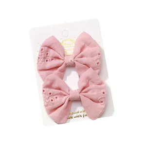 Set of two pink embroidered fabric bow hair clips for kids on a white display card