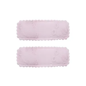 Detailed view of two pink embroidered rectangular hair clips with scalloped edges.
