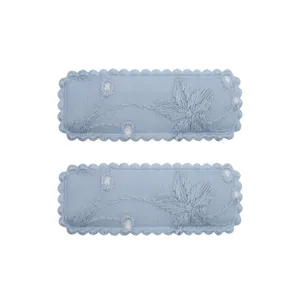 Macro detail showing light blue embroidered fabric hair clips with floral pattern