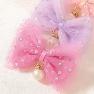 Dettaglio di fermagli per capelli con fiocco in tulle e pendenti in perla bimba
