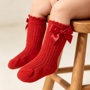 Detailansicht von süßen roten Strick-Babysöckchen mit dekorativen Satinschleifen Verzierung