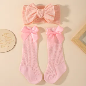 Nahaufnahme von rosa Strickstirnband und Socken mit dekorativen Satinschleifen
