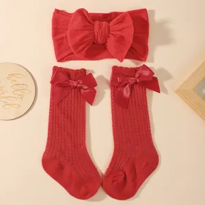 Nahaufnahme von rotem Baby-Stirnband- und Socken-Set mit dekorativen Satinschleifen
