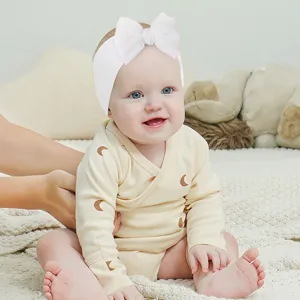 Detailed view of white pleated bow headband worn by a baby, showcasing soft fabric texture.