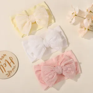 Soft pleated baby headbands featuring large shiny bows in yellow, white, and pink colors.
