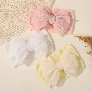 Detail of baby headbands with large lace bows in pink, white, and yellow colors