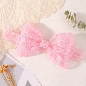 Gros plan sur un bandeau pour bébé en dentelle rose avec un nœud et motif floral