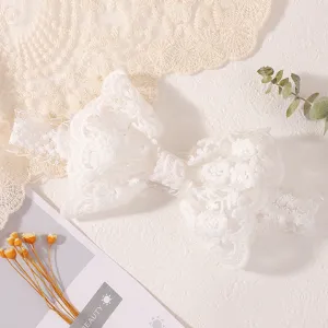 Gros plan d'un bandeau en dentelle blanche à fleurs avec un nœud pour bébés aux motifs délicats
