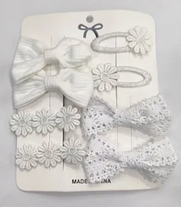 Vista detallada de un set de horquillas blancas con lazos de tela y flores bordadas