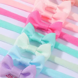 Detailed close-up of colorful elastic nylon baby headbands with grosgrain ribbon bows.