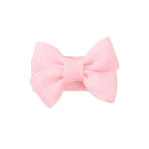 Close-up of a solid pink grosgrain ribbon bow hair clip for babies and young children