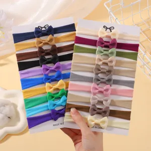 High-quality set of multi-colored bowknot baby headbands shown on cardboard display.