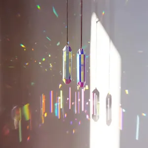 Detalle de atrapasoles de cristal irisado que refractan luz de arcoíris en una pared.