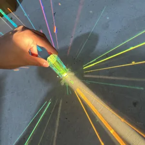 Primer plano de un prisma atrapasol de cristal que crea vivos reflejos de arcoíris.