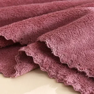 Close-up detail shot of soft coral fleece towel fabric showing plush texture and scalloped edges.