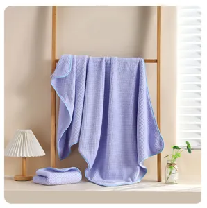 Vista dettagliata del grande telo bagno waffle viola appeso su un supporto in legno.